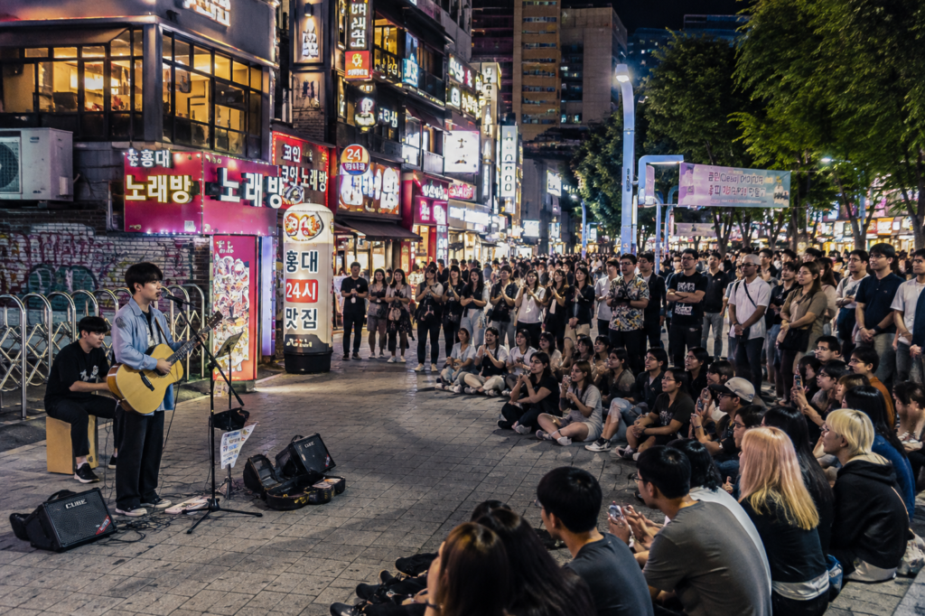 Street busking performance in Hongdae Seoul with people watching at night
